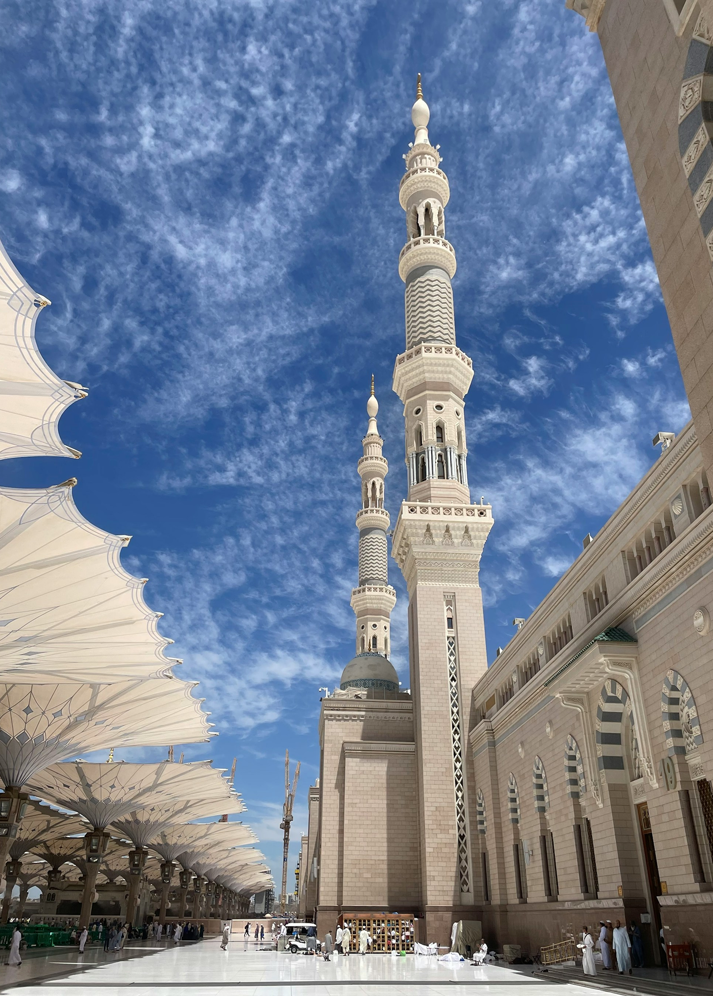 Al-Masjid an-Nabawi in Medina with minarets and umbrellas under a blue sky